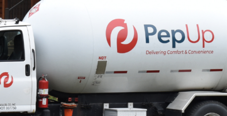 A PepUp propane delivery truck is parked in front of a home while the customer's propane tanks are filled.