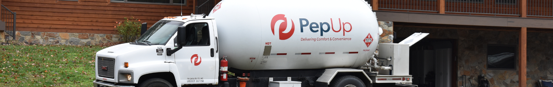 A PepUp propane delivery truck is parked in front of a home while the customer's propane tanks are filled.