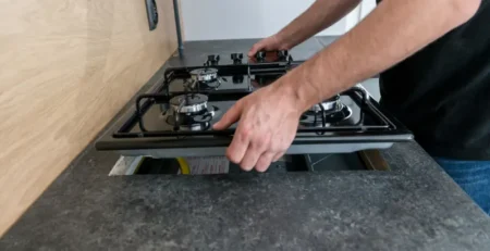 Image of a worker installing a propane cook top, an essential swap when upgrading electric to propane appliances.