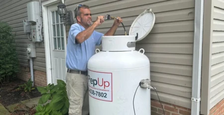 A PepUp technician inspects a 124-gallon propane tank regulator at a residence in Delaware prior to completing a pressure test and safety check, fall 2025.