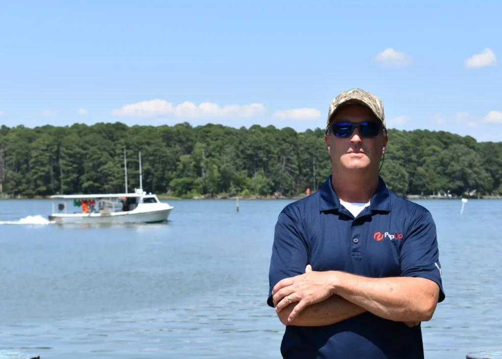 Image of Jacob Abbott, ag sales rep for PepUp, posing with a boat on the water in the background.