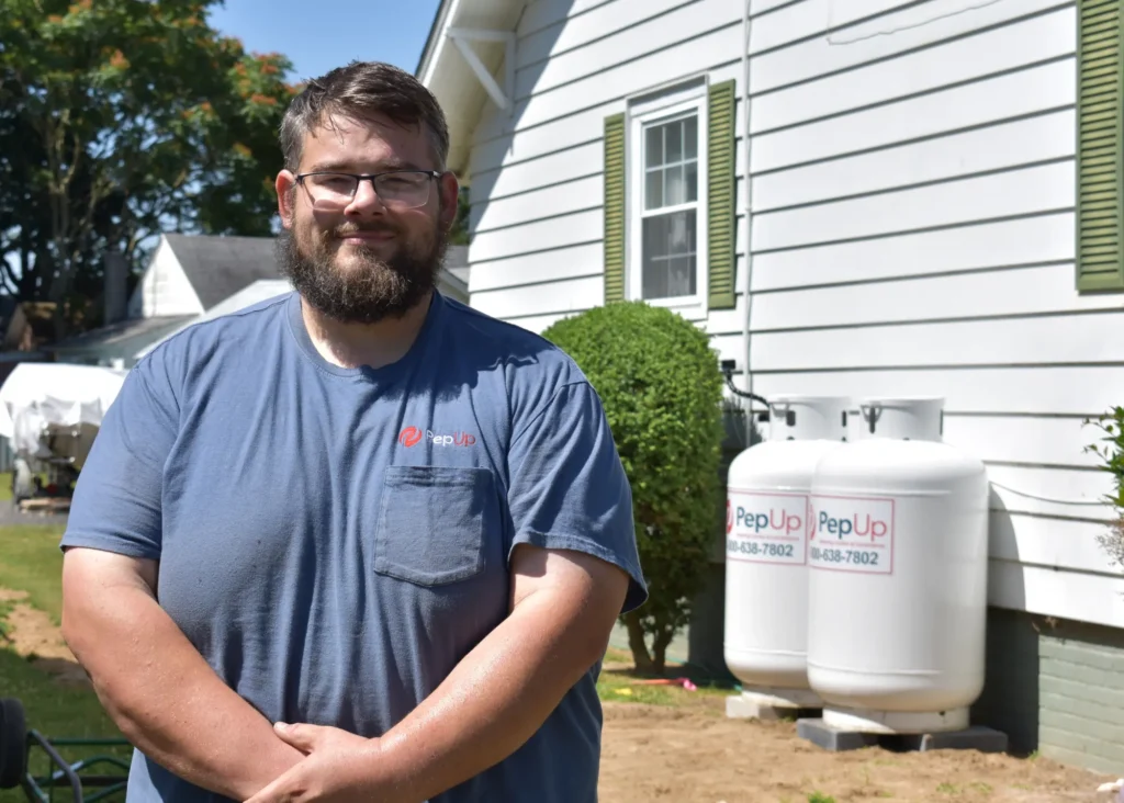 An image of PepUp Delivery Driver and Blog Contributor Kevin Gowe, outside a home with PepUp propane tanks.