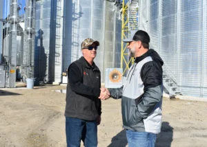 A PepUp Propane Salesman shakes hands with a local Delmarva farmer, with grain silos in the background.