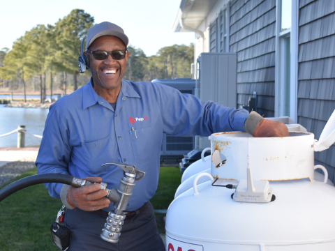 Image of propane delivery driver Ben Fulton, smiling while standing by a propane tank.