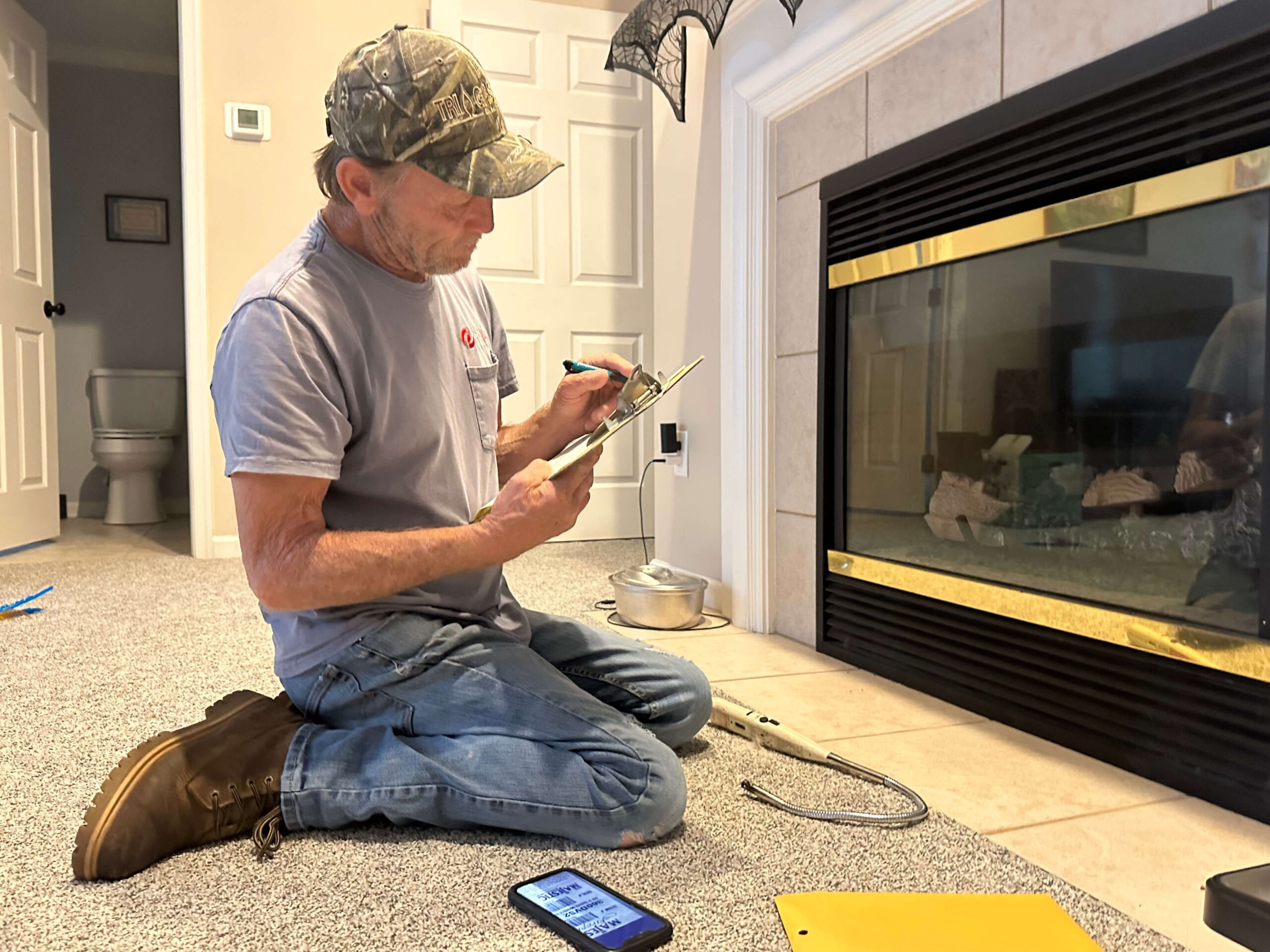 A PepUp technician cleans a propane fireplace during a routine seasonal tune-up.