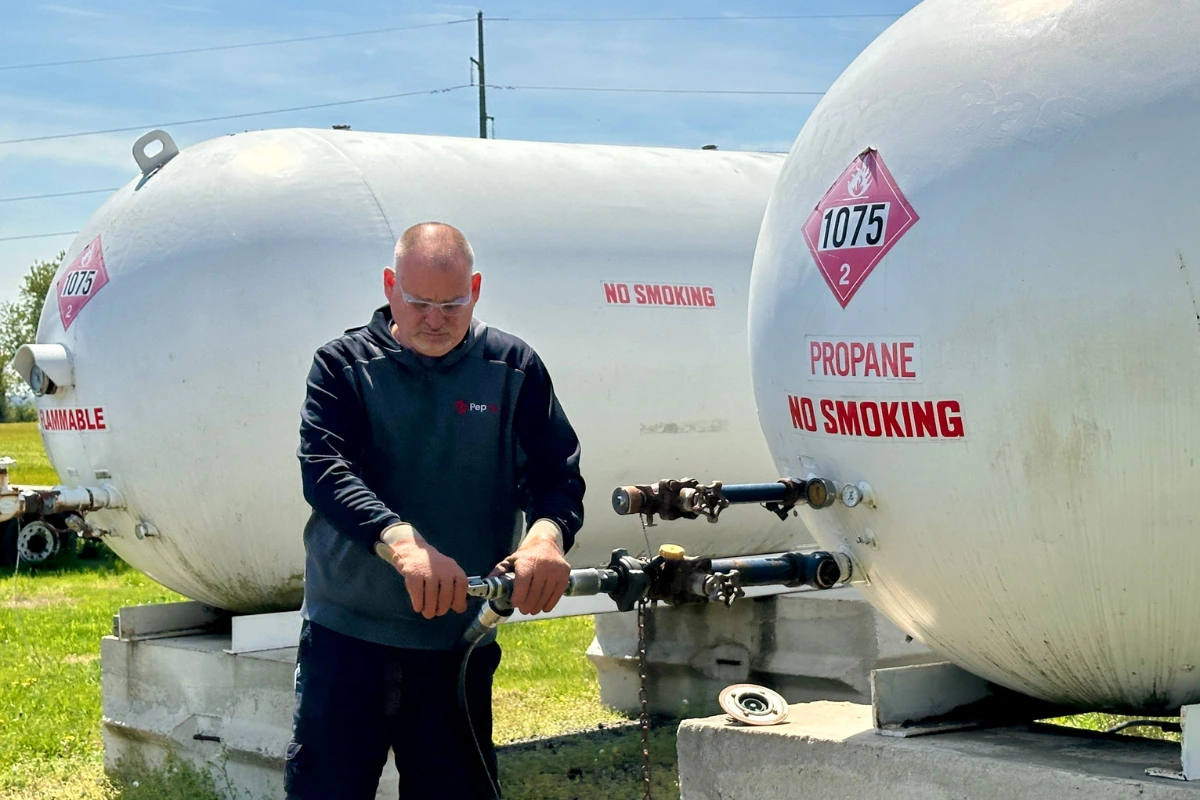 A PepUp delivery driver prepares to fill industrial-sized propane tanks during a manufacturing fuel delivery service.