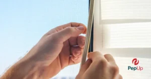 A close-up image of a homeowner on Delmarva replacing window weatherstripping to prevent heat loss.