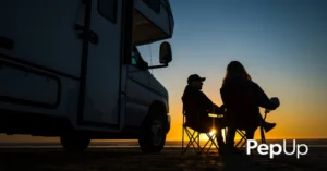 A couple watches the sunset while sitting beside a small RV while camping near Chesapeake Bay.