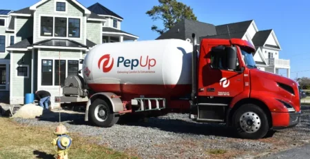 A PepUp propane delivery truck in front of a home on Delmarva, filling a tank after the customer converted to propane from heating oil.